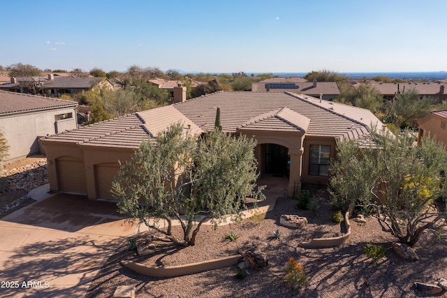 view of front of property featuring a tile roof, a garage, driveway, and stucco siding