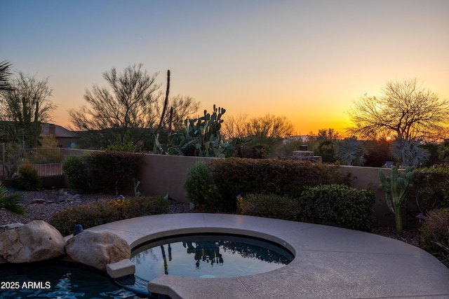 pool at dusk featuring fence