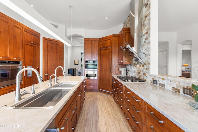 kitchen with visible vents, a sink, tasteful backsplash, stainless steel gas stovetop, and light stone countertops