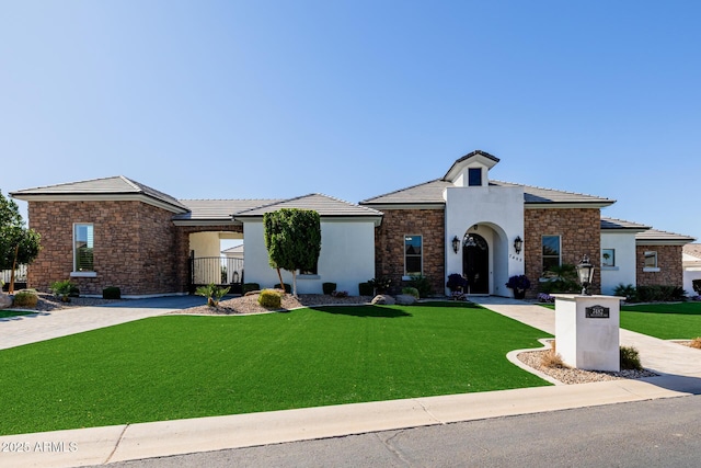 view of front facade with a front lawn, a tile roof, stone siding, and stucco siding