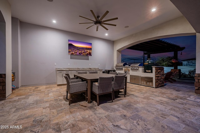 dining space featuring arched walkways, recessed lighting, stone finish floor, and ceiling fan