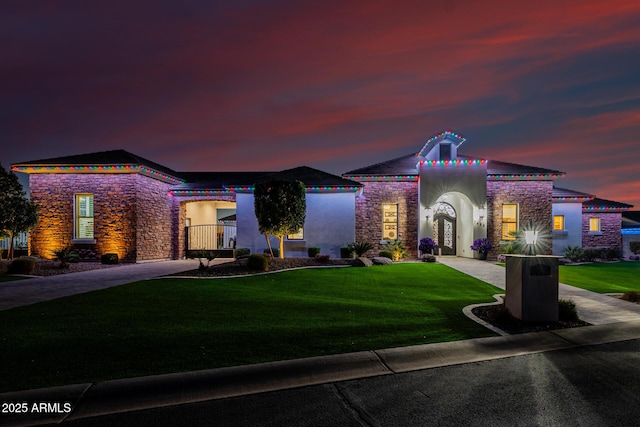 view of front of house featuring a lawn, stone siding, and stucco siding