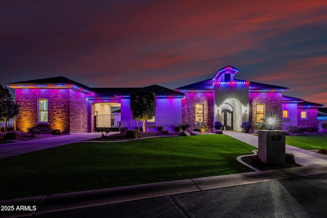 view of front of home with stucco siding, stone siding, and a front lawn