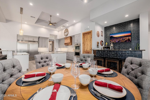 dining room with visible vents, a tray ceiling, a high ceiling, recessed lighting, and ceiling fan