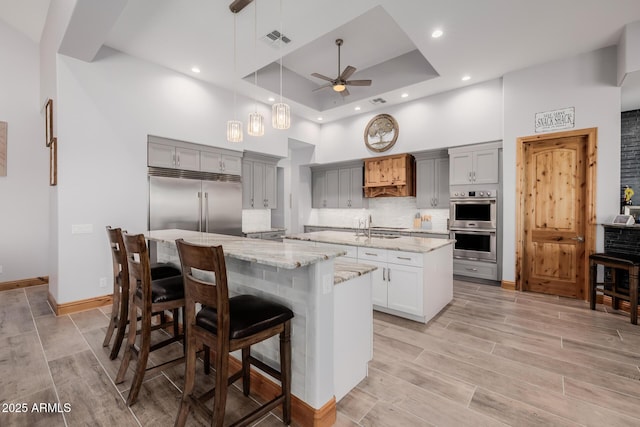 kitchen with a ceiling fan, visible vents, an island with sink, gray cabinetry, and appliances with stainless steel finishes