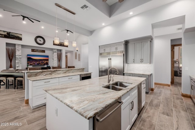 kitchen featuring visible vents, a sink, a spacious island, stainless steel appliances, and ceiling fan