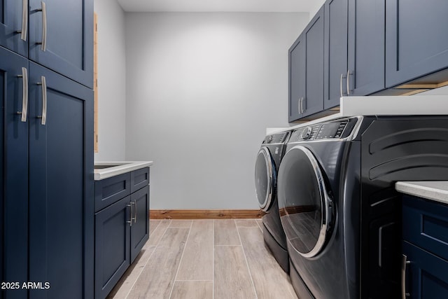 clothes washing area with baseboards, cabinet space, wood tiled floor, and washer and clothes dryer