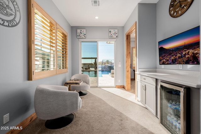 living area with visible vents, beverage cooler, recessed lighting, baseboards, and light colored carpet