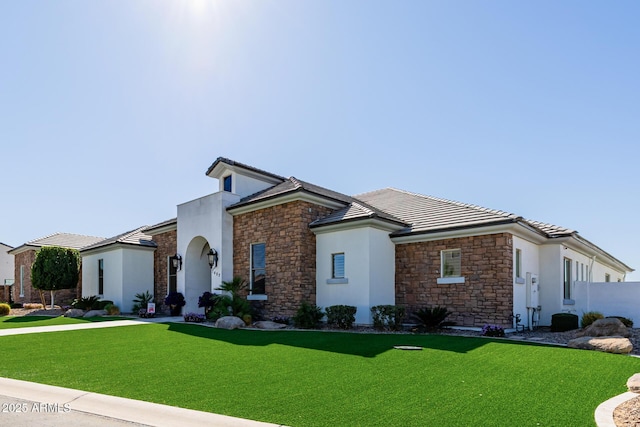 view of front facade featuring stone siding, stucco siding, a tile roof, and a front yard