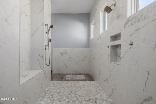 bathroom featuring a marble finish shower and tile walls