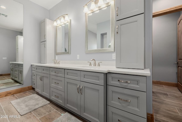 bathroom featuring a sink, baseboards, double vanity, and wood tiled floor