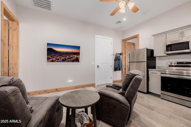 interior space with light wood-style flooring, a ceiling fan, visible vents, and baseboards