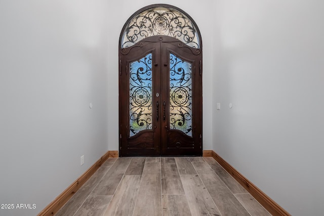 entrance foyer featuring wood finished floors, french doors, and baseboards