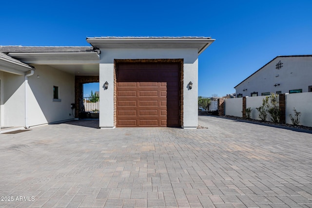 garage with decorative driveway and fence