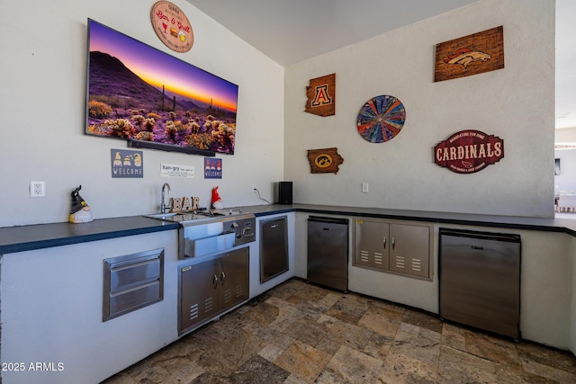 bar with a sink, fridge, indoor wet bar, and stone finish flooring