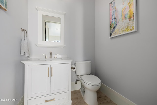 bathroom featuring vanity, toilet, and baseboards