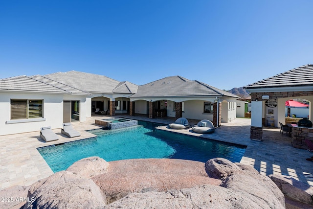 view of swimming pool featuring outdoor dry bar, a pool with connected hot tub, and a patio