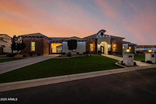 view of front of property featuring stucco siding, a lawn, driveway, a gate, and fence