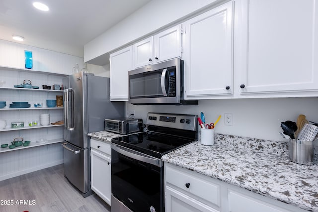 kitchen with white cabinets, appliances with stainless steel finishes, and light stone counters