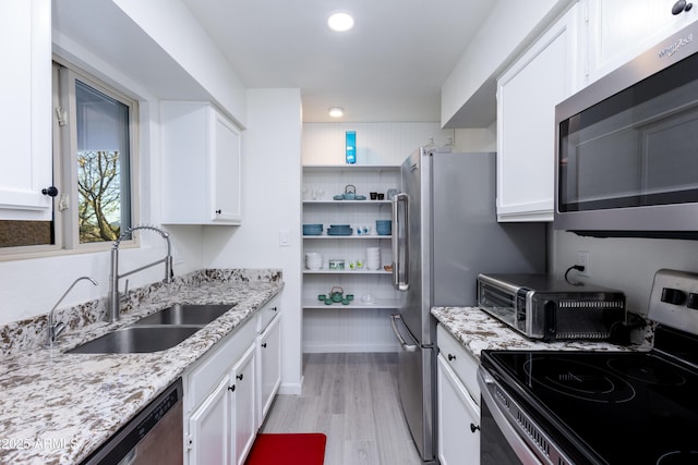 kitchen featuring light hardwood / wood-style floors, sink, appliances with stainless steel finishes, white cabinets, and light stone counters