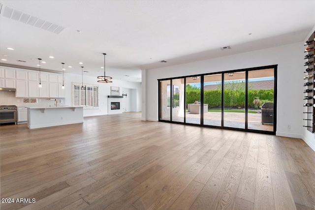 unfurnished living room featuring light wood-type flooring and sink