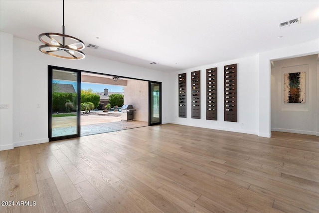 unfurnished living room featuring light hardwood / wood-style flooring and a notable chandelier