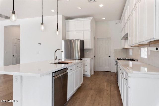 kitchen featuring stainless steel appliances, a kitchen island with sink, sink, decorative light fixtures, and white cabinetry