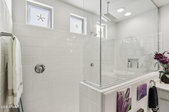 bathroom with tiled shower and vanity