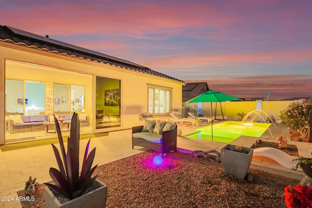 patio terrace at dusk with a fenced in pool, pool water feature, and an outdoor hangout area