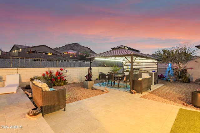 patio terrace at dusk with a gazebo, an outdoor living space, and a mountain view