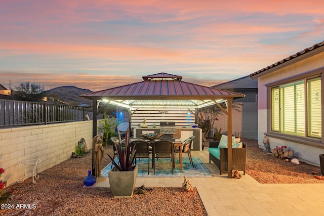 patio terrace at dusk featuring a gazebo, grilling area, and a mountain view