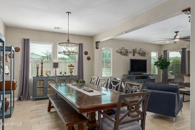 dining space with a healthy amount of sunlight, ceiling fan with notable chandelier, and light hardwood / wood-style flooring