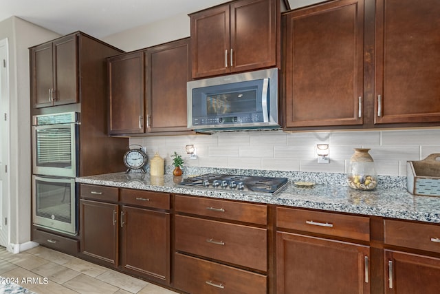 kitchen featuring stainless steel appliances, light stone counters, and backsplash