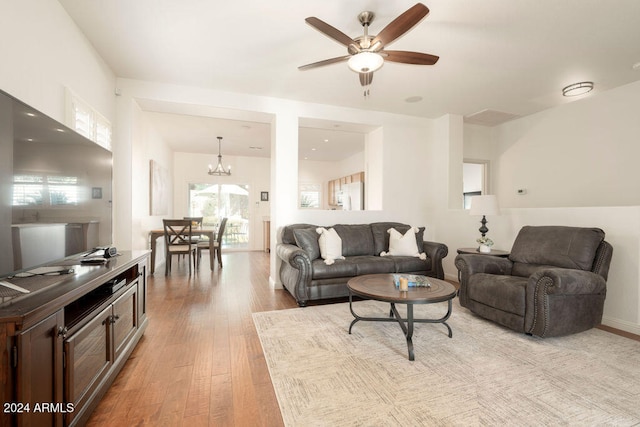 living room with light hardwood / wood-style floors and ceiling fan with notable chandelier