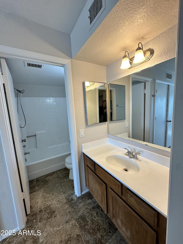 full bathroom with washtub / shower combination, vanity, a textured ceiling, and toilet