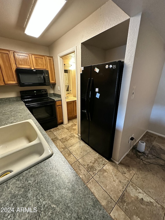 kitchen featuring black appliances, light tile patterned flooring, and sink