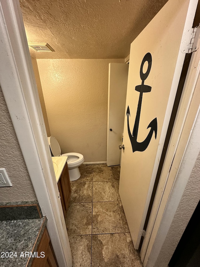 bathroom featuring vanity, toilet, and a textured ceiling