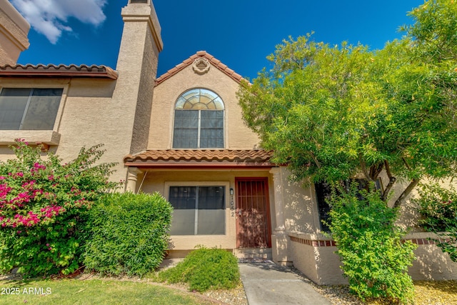 4901 E Kelton Ln Unit 1052, Scottsdale, AZ 85254 - doorway to property featuring a tiled roof, stucco siding, and a chimney