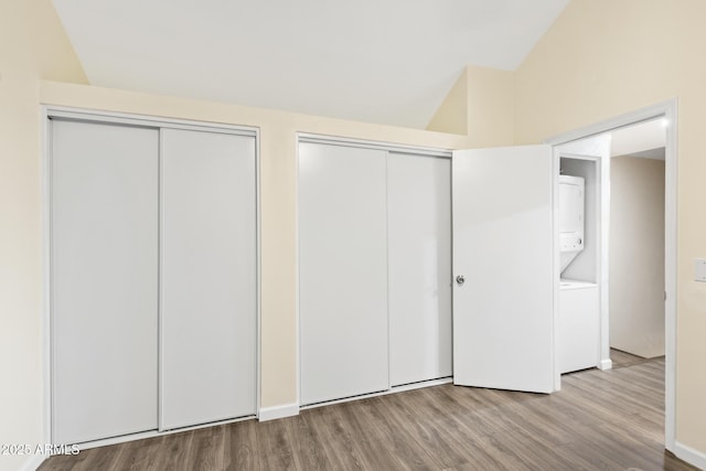 4901 E Kelton Ln Unit 1052, Scottsdale, AZ 85254 - unfurnished bedroom featuring stacked washer / dryer, multiple closets, wood finished floors, and lofted ceiling