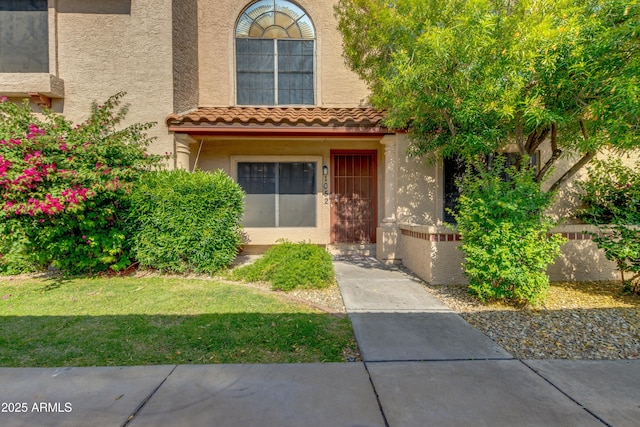 4901 E Kelton Ln Unit 1052, Scottsdale, AZ 85254 - view of exterior entry featuring stucco siding, a tile roof, and a lawn