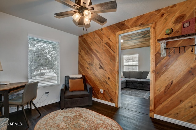 sitting room featuring dark hardwood / wood-style floors, ceiling fan, and wood walls