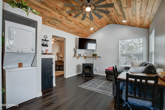 living room featuring lofted ceiling, stacked washer / dryer, dark hardwood / wood-style flooring, wooden ceiling, and a wood stove