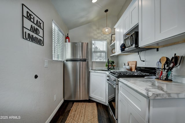 kitchen featuring vaulted ceiling, appliances with stainless steel finishes, white cabinetry, hanging light fixtures, and dark wood-type flooring