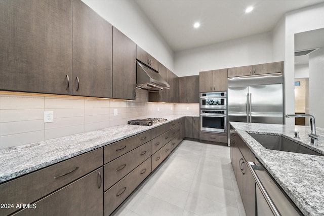 kitchen featuring sink, light stone countertops, appliances with stainless steel finishes, and tasteful backsplash