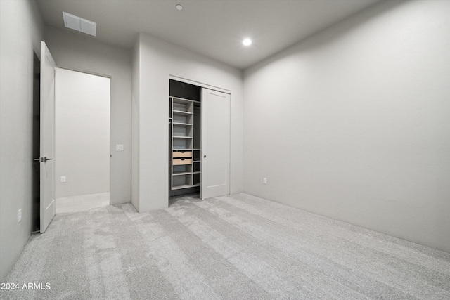 unfurnished bedroom with a closet and light carpet