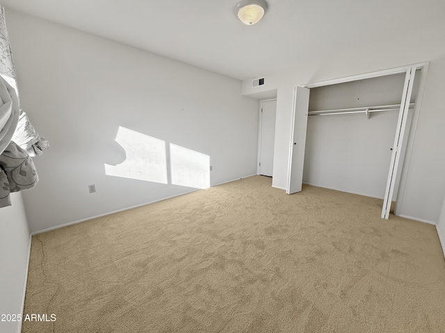 unfurnished bedroom with light colored carpet and a closet