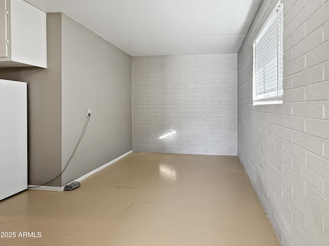 basement featuring brick wall and fridge