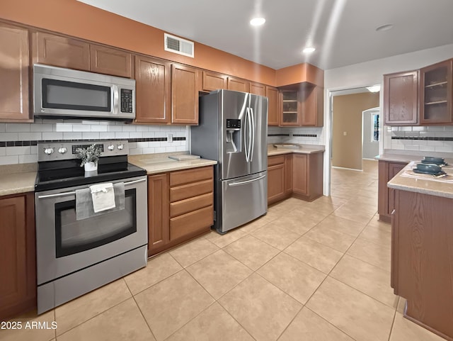 kitchen featuring stainless steel appliances, light tile patterned floors, and decorative backsplash