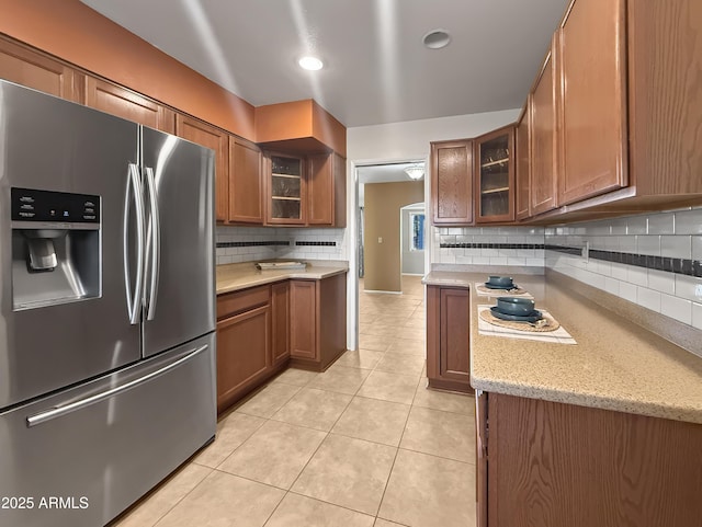 kitchen featuring light stone counters, stainless steel fridge, backsplash, and light tile patterned flooring