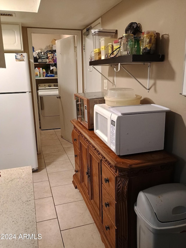 clothes washing area with light tile patterned floors